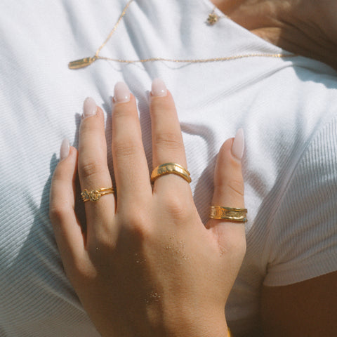 Petals ring in 24ct gold plate — worn with two textured gold bands in sunlight