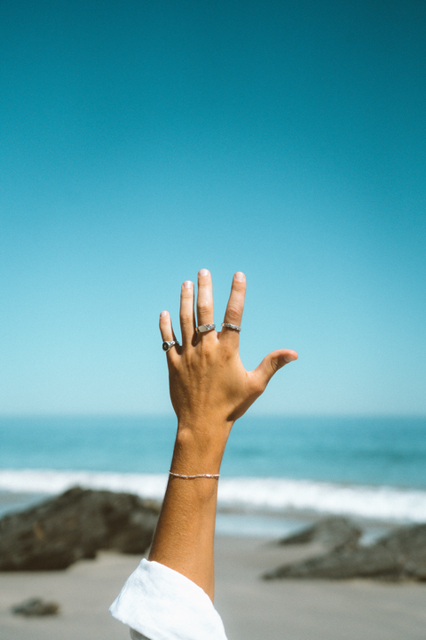 Lou's Stacker in sterling silver — worn with mixed silver rings against the ocean sky