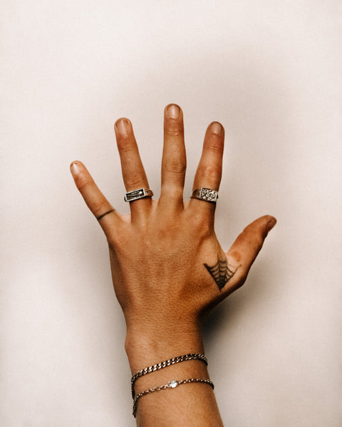 Lou's Cuban in sterling silver — worn below a fine chain bracelet with rings visible