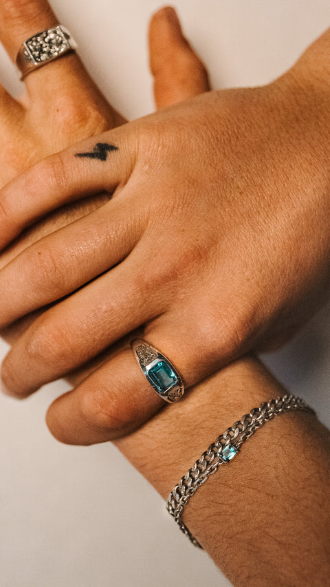 Nascence frangipani ring in sterling silver — partially visible beside a blue-stone ring