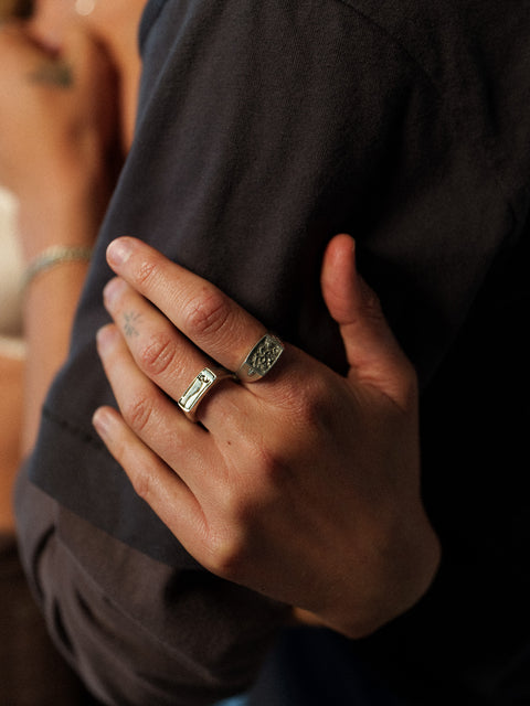 Nascence frangipani ring in sterling silver — angled worn close-up against dark fabric