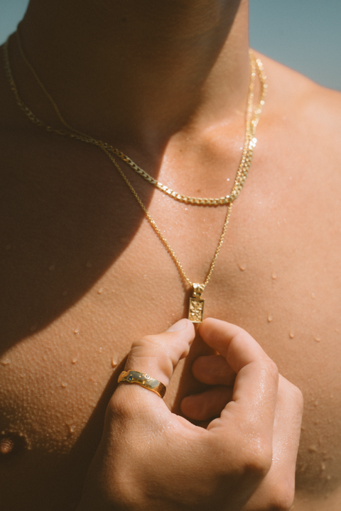 Coalesce ring in 24ct gold plate — worn while holding a rectangular gold pendant