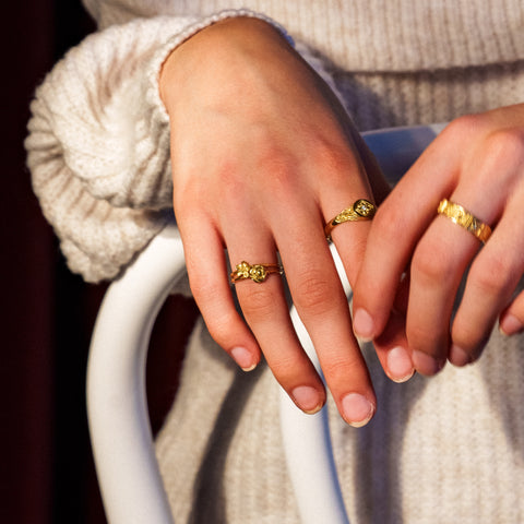 Petals ring in 24ct gold plate — worn with two other gold rings in a seated portrait