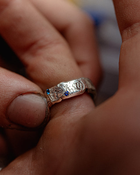 Lou's Grad Ring in sterling silver — held between fingers with the engraved band visible