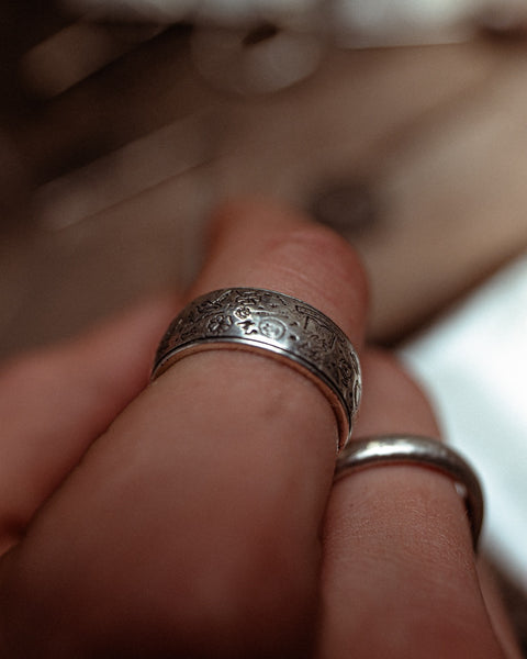 The Grad Ring in sterling silver — worn close-up with engraved symbols visible