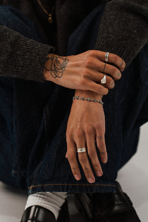 Coalesce ring in sterling silver — worn with other silver rings in a seated portrait