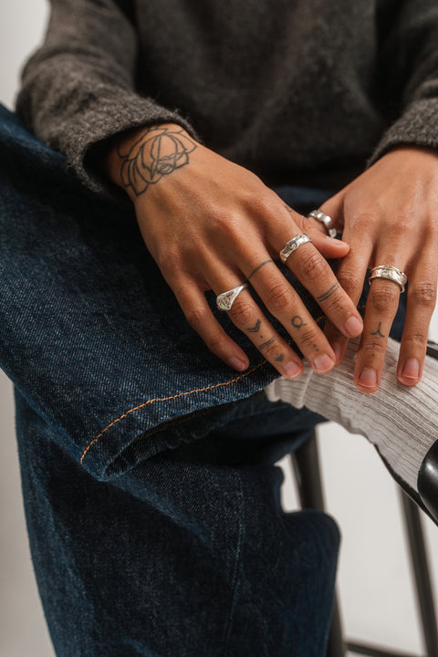 Coalesce ring in sterling silver — worn with multiple rings in a seated close-up