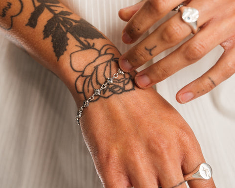 Signature Bracelet in sterling silver — close-up worn across a tattooed wrist