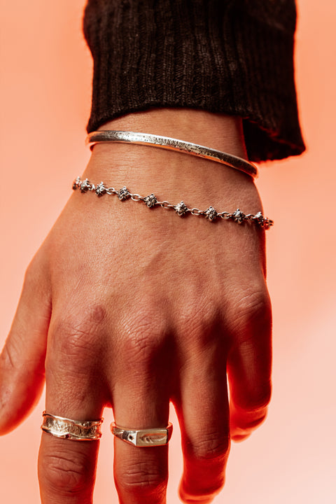 Signature Bracelet in sterling silver — close-up worn on the hand beneath a silver cuff
