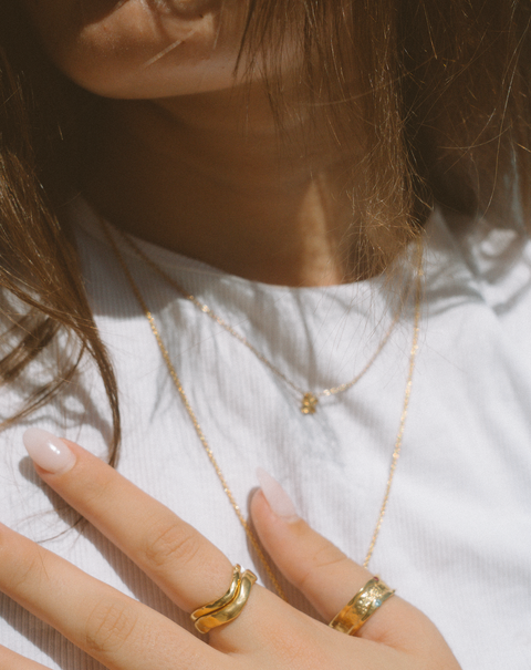 Serene I ring in 24ct gold plate — worn beside a textured gold band in sunlight