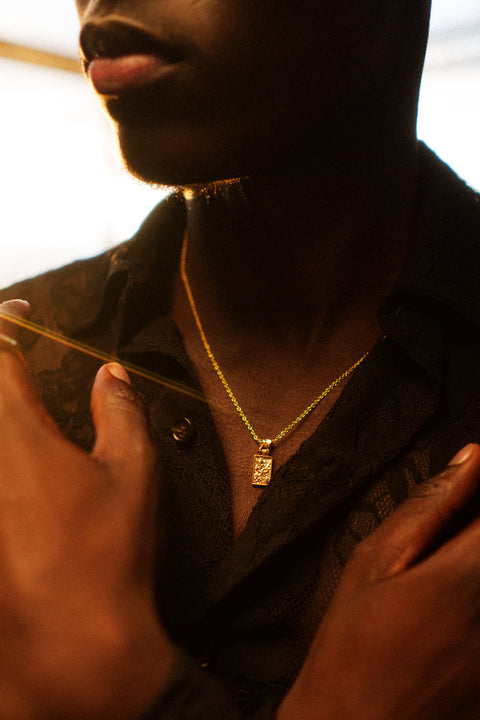 Nascence Pendant in 24ct gold plate — worn at chest length in a warm-lit close-up