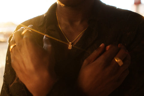 Nascence Pendant in 24ct gold plate — worn with gold rings in a sunlit portrait